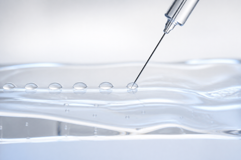 A fine needle depositing small even micro-deposits into a translucent gel surface, illustrating mesotherapy as a technique