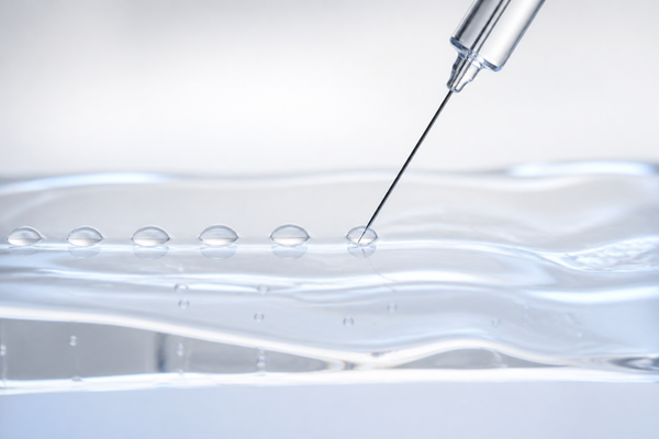 A fine needle depositing small even micro-deposits into a translucent gel surface, illustrating mesotherapy as a technique